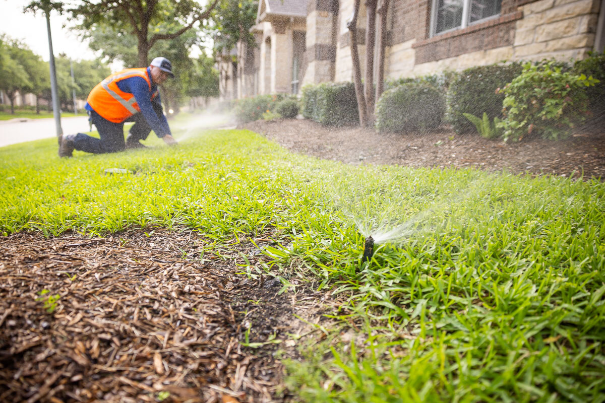 irrigation technician adjusts sprinkler system spray heads