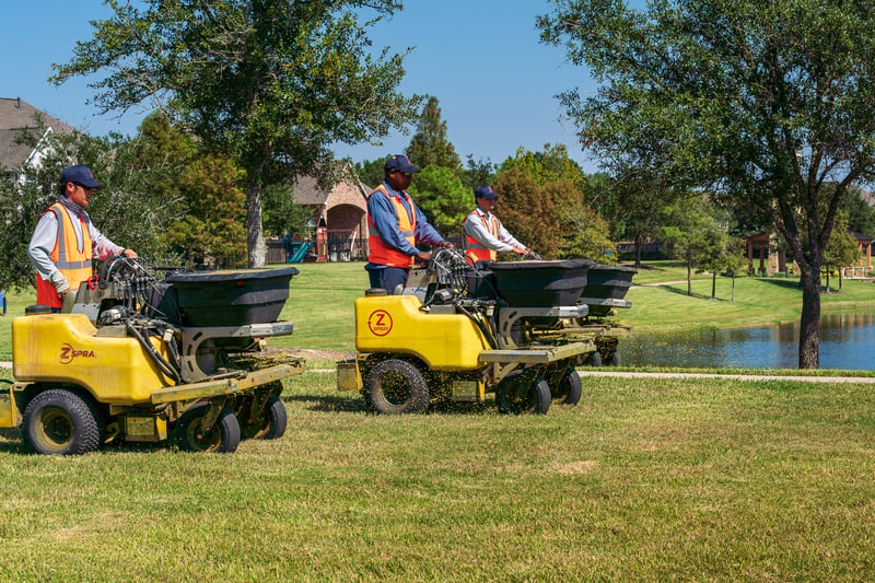 team fertilizes lawn at commercial property on ride-on machines