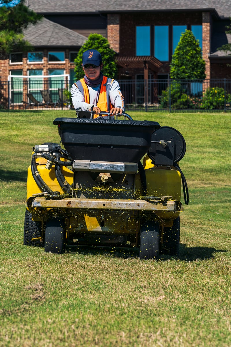 lawn care team spreads fertilizer on lawn