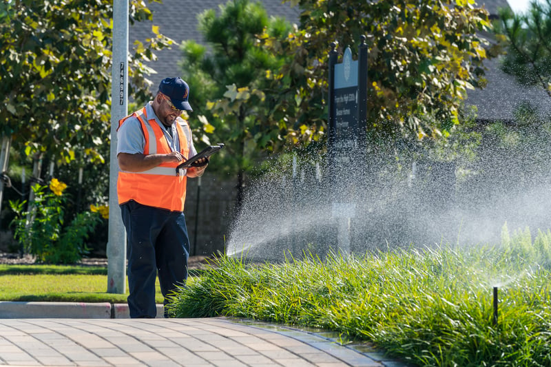 irrigation technician inspects sprinkler system