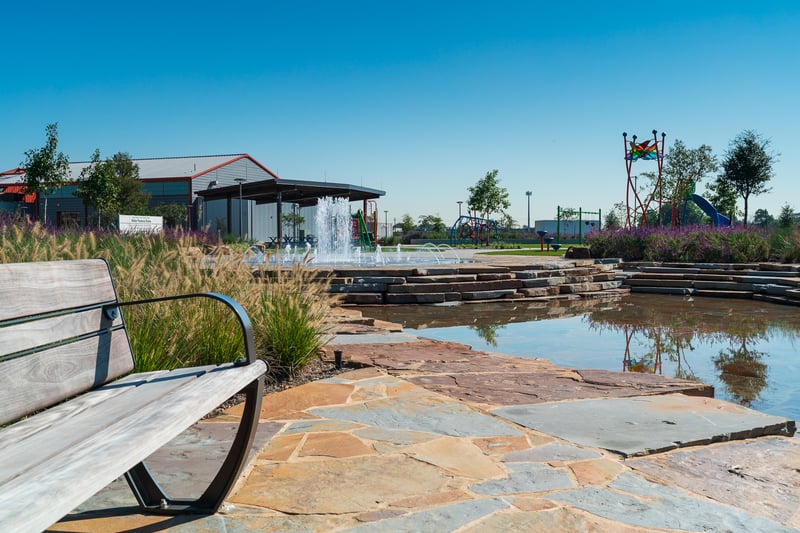 hardscape area with splash pad and playground with plantings