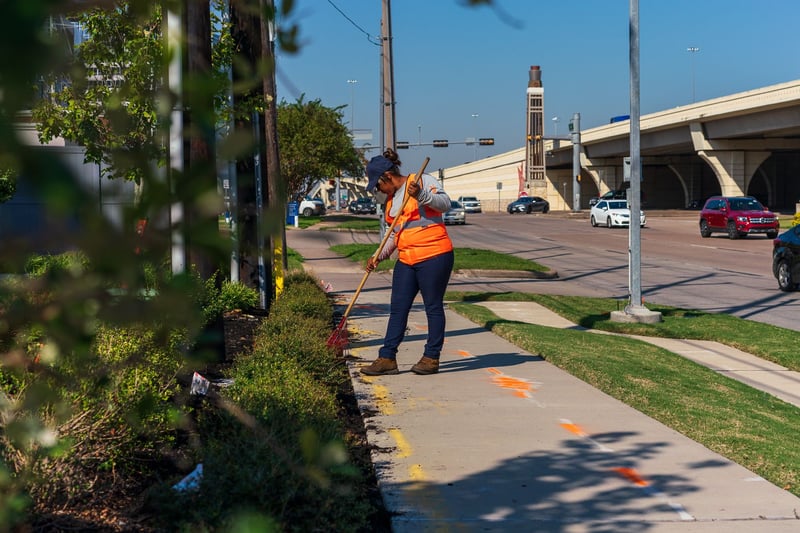 landscape maintenance team spreads mulch near busy road